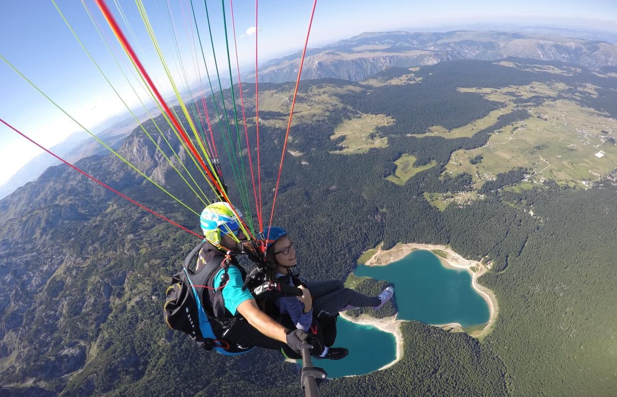 Tandem paraglider flying above Black Lake and Durmitor National Park in northern Montenegro